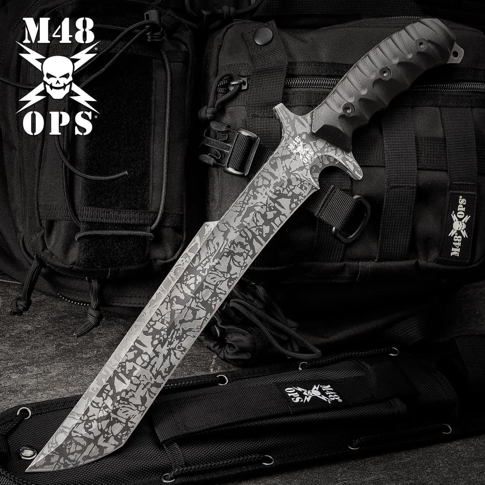 17 3/4" titanium electroplated finish blade M48 combat machete with black TPU handle on a background of black utility gear. image number 0