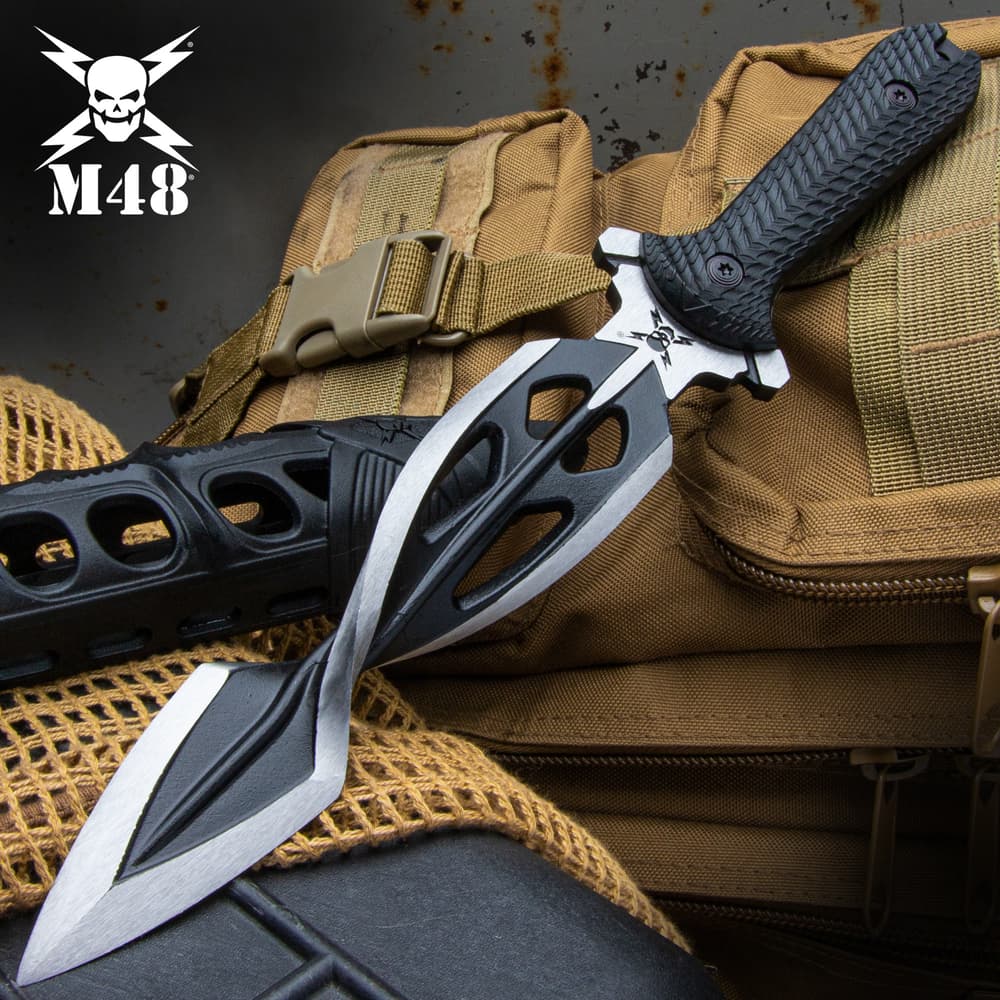 The M48 Tsunami Dagger has a twisted two-tone satin blade with custom sheath, shown on a tactical background. image number 0