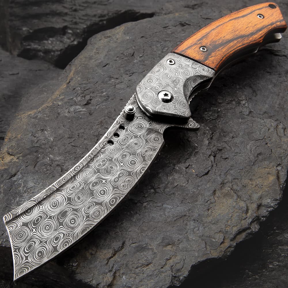 The Boot Hill Razor Pocket Knife is shown with 3 1/2" Damascus patterned stainless steel blade and wooden handle on a dark rock background. image number 0