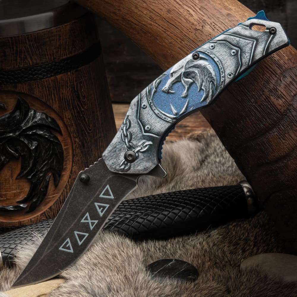 This witcher pocket knife ofers an assisted opening blade and runes etches into the blade. image number 0