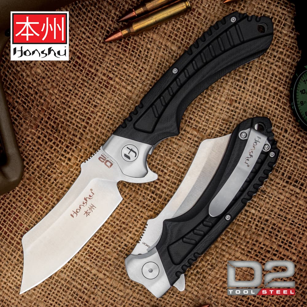 The Honshu Sekyuriti Razor Pocket Knife has a D2 tool steel blade with thumb notches and black G10 handle scales, shown on brown background. image number 0