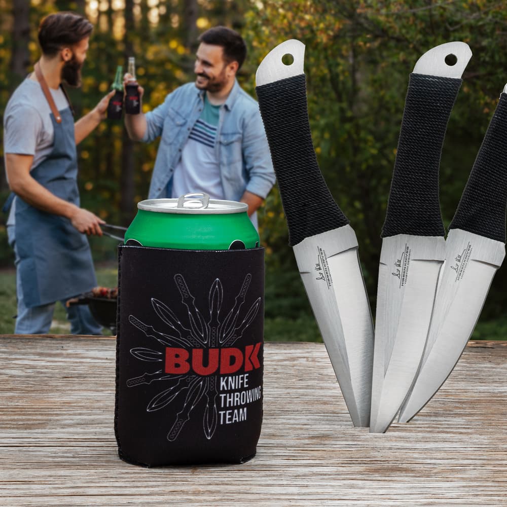 A black koozie is shown, printed with red and black "BUDK KNIFE THROWING TEAM" lettering and white fanned knife graphic. image number 0