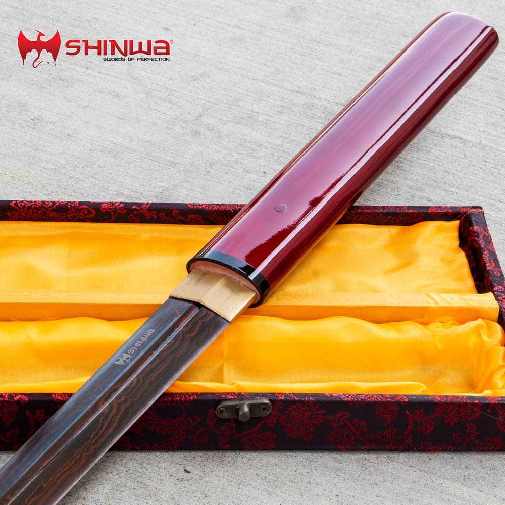 Shinwa ScarletFang Shirasaya Sword has a red lacquered hardwood handle, shown atop ornate display box. image number 0