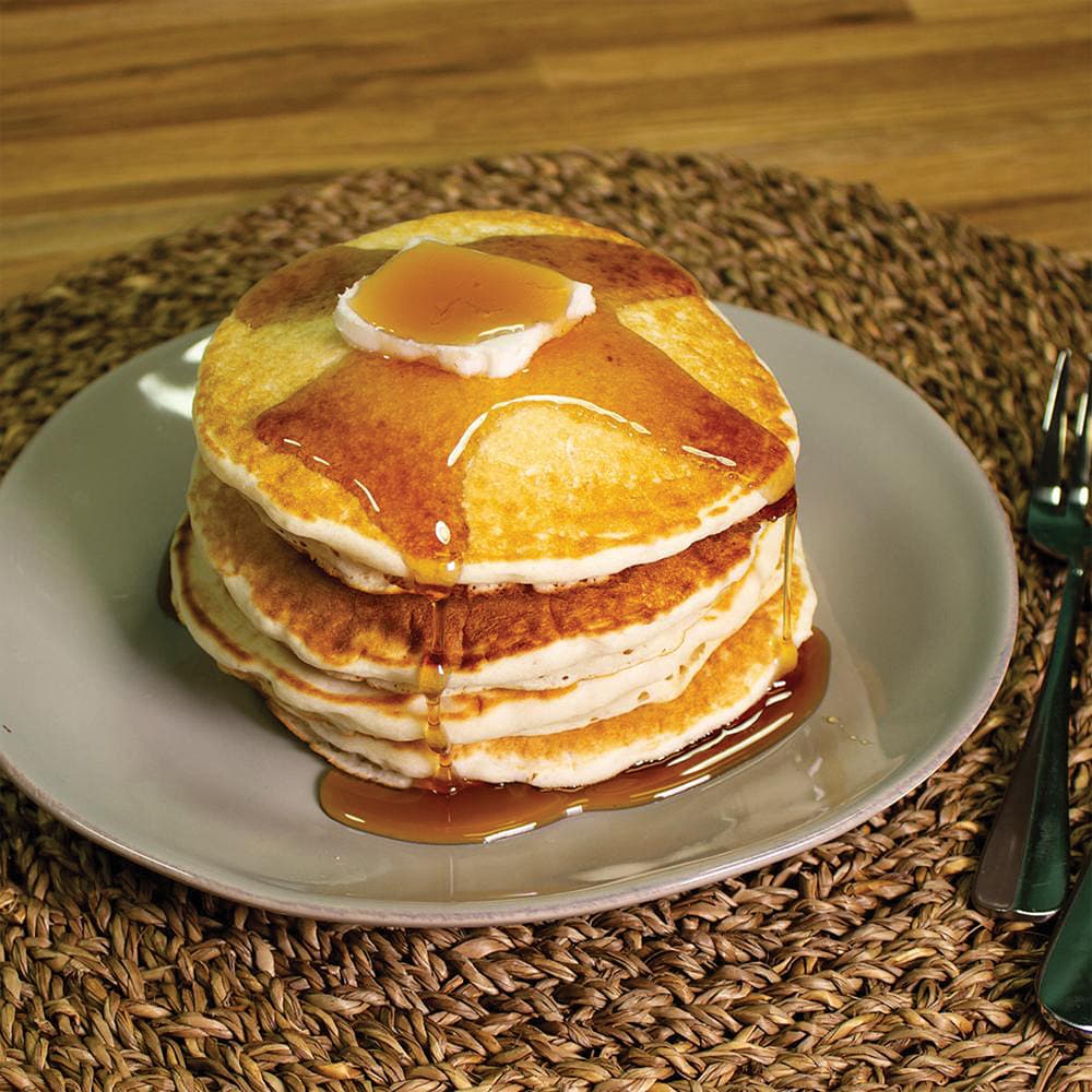 A stack of pancakes from the Emergency Essentials 6-Month Food Kit shown covered in syrup on a green plate with fork. image number 1