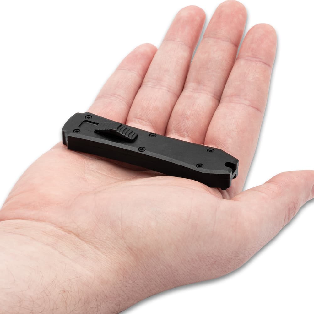 Closed small non-reflective black automatic OTF knife with small hole at the bottom center and sliding trigger button. image number 1