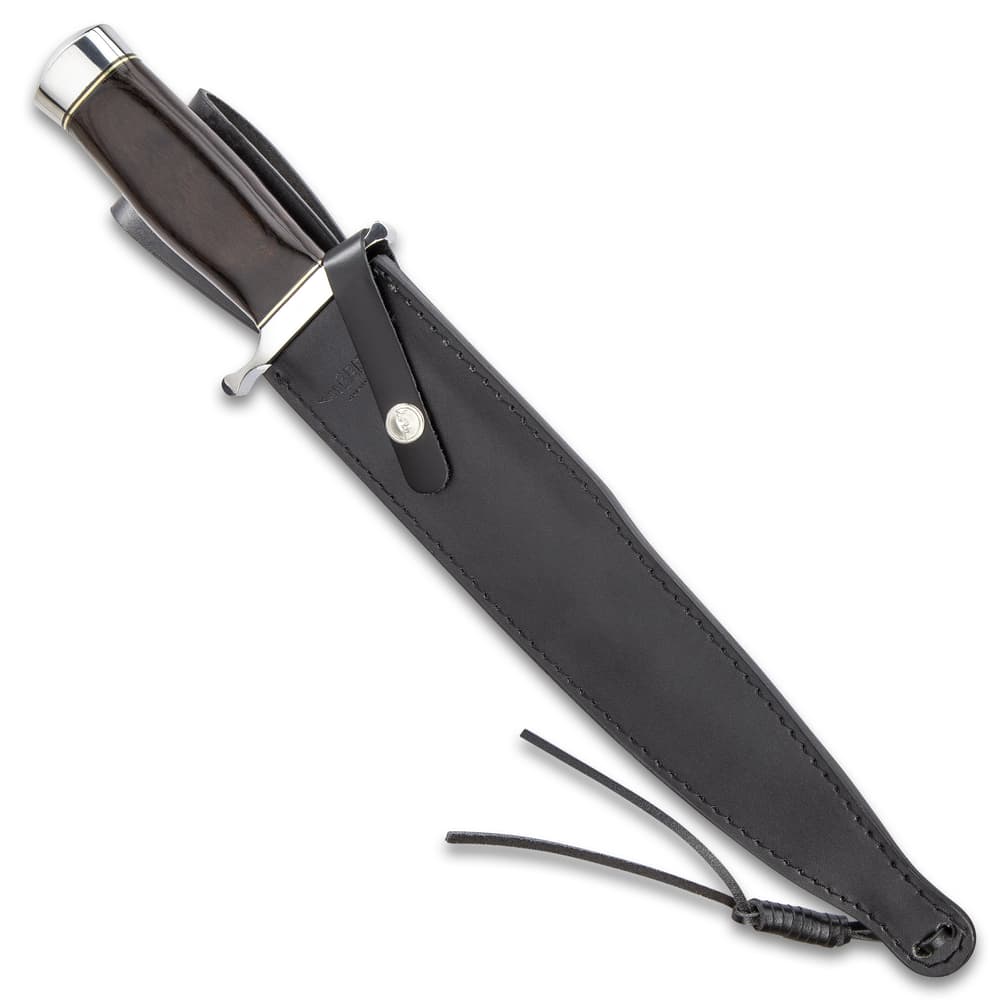 The knife housed in a black genuine leather sheath with a strap. image number 1