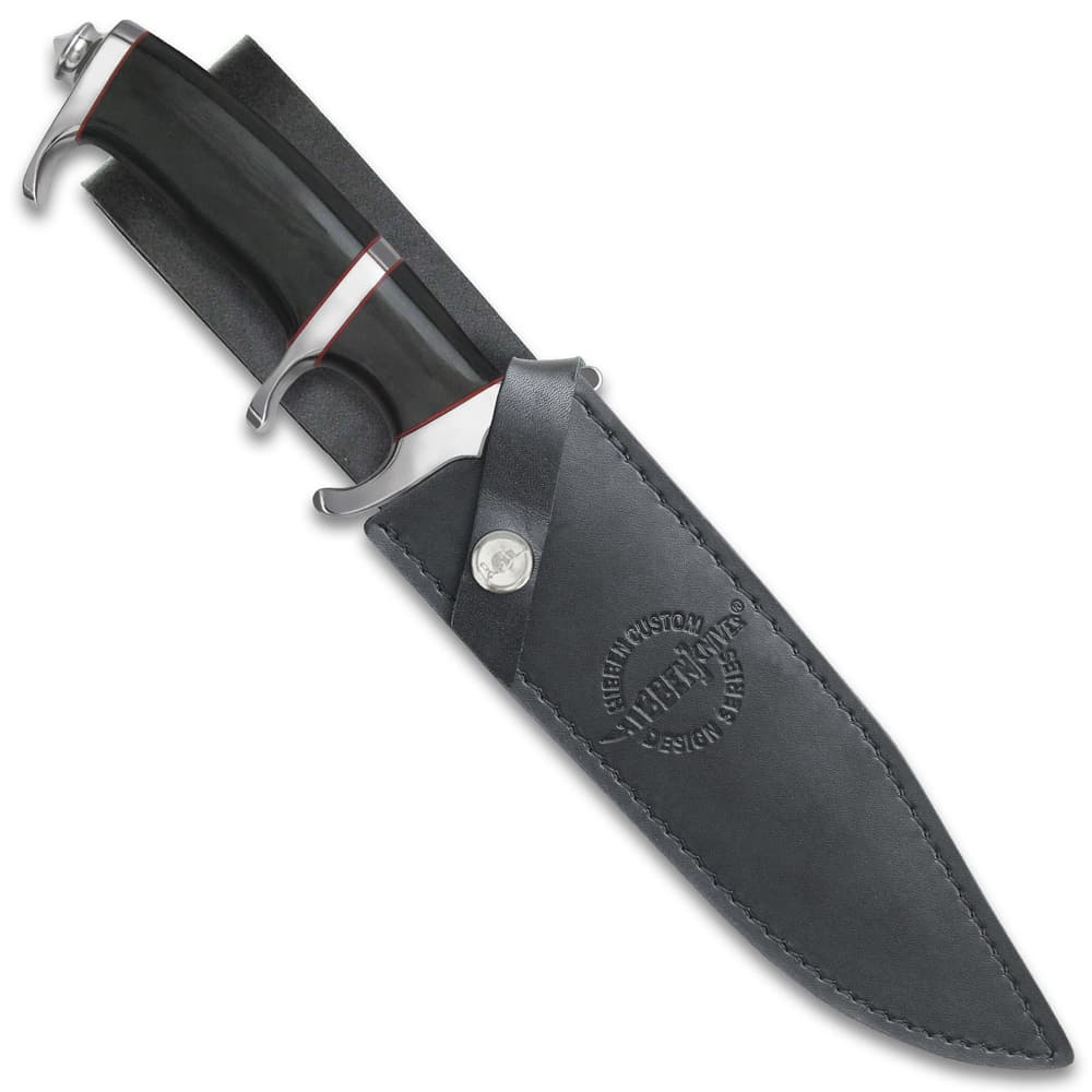 Large knife with black, red, and silver, hilt exposed with the blade enclosed in a black leather sheath stamped with "Hibben Knives" logo image number 1
