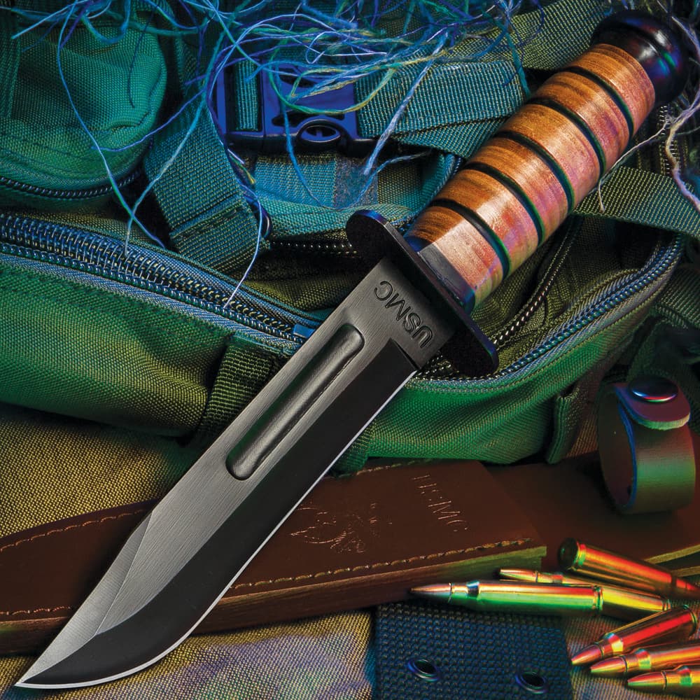 7" black finished steel blade fighter knife with a stacked leather handle on a background of green utility gear. image number 1
