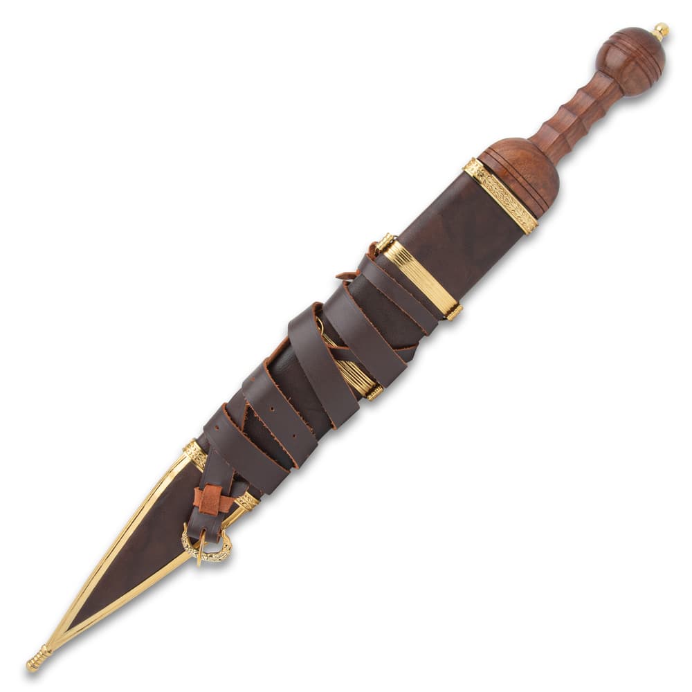 The Roman Mainz Pattern Gladius is shown house in its brown leather scabbard with straps and brass colored detailing. image number 1