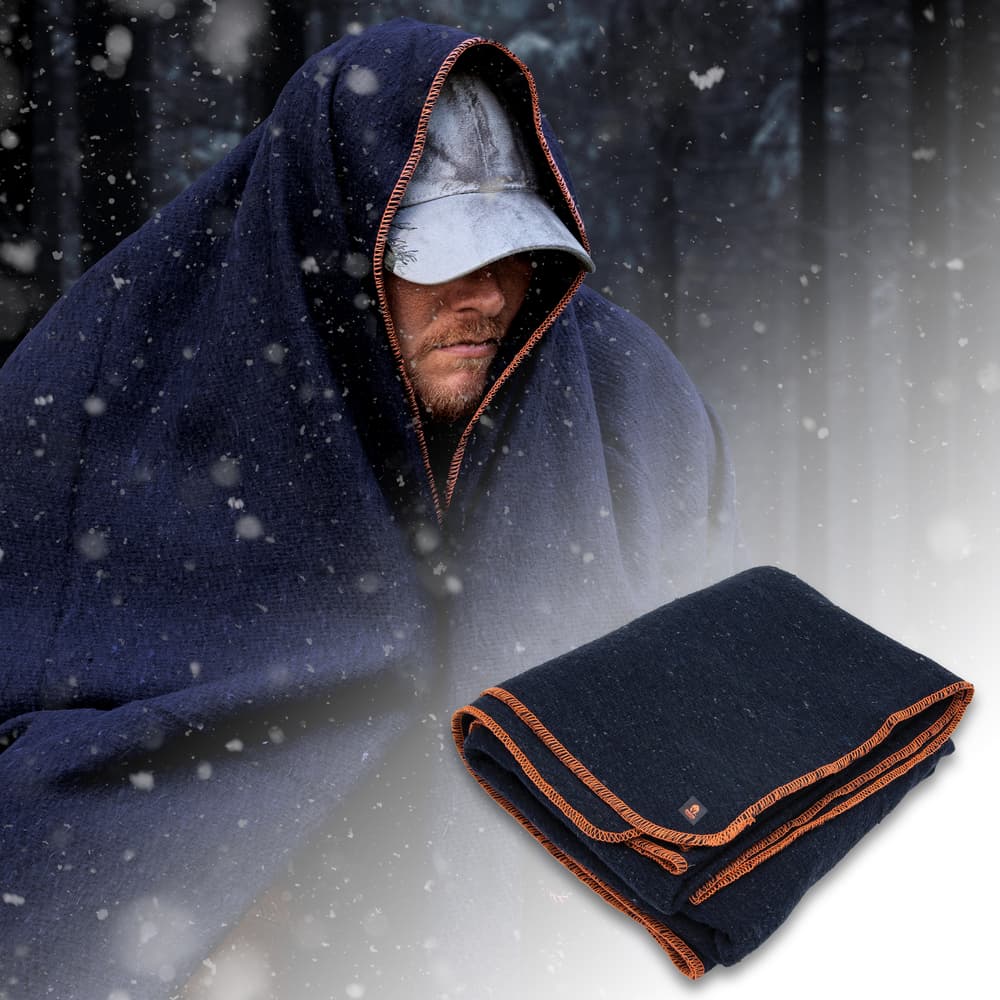 The Spartan Wool Blanket made to keep you warm and dry is shown folded and draped over a man in the snow. image number 2