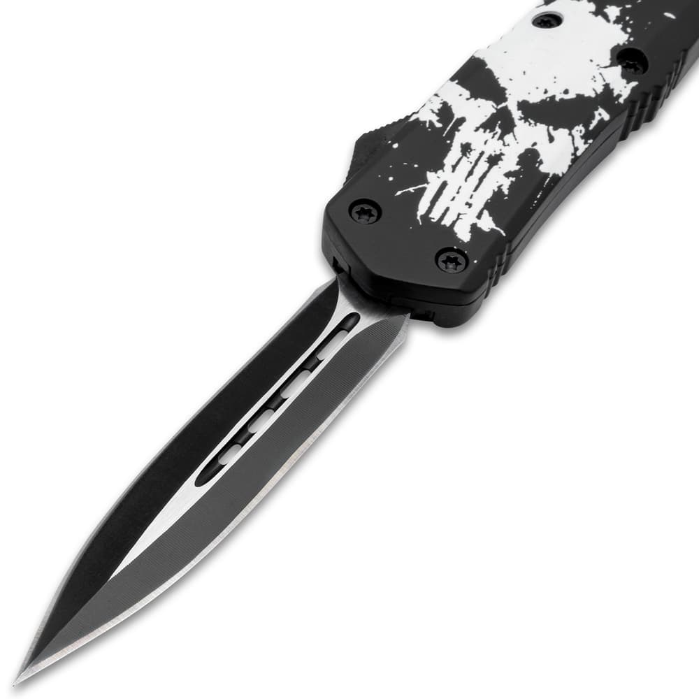 Upclose view of an open OTF pocket knife with a matte black and silver dual toned dagger style blade and a blade handle with a large white distressed skull print. image number 2