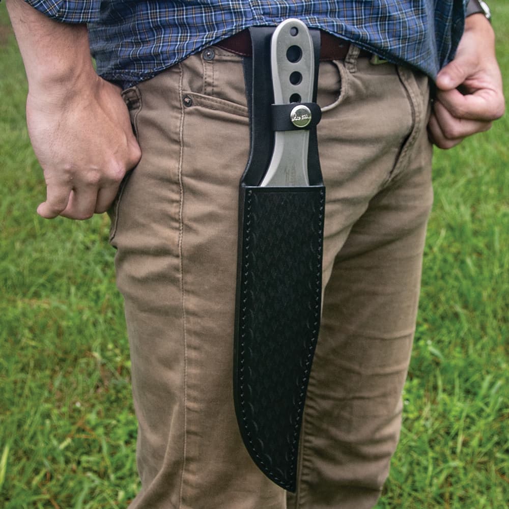 Polished throwing kife enclosed in black leather sheath attached to a belt positioned on top of the leg. image number 2