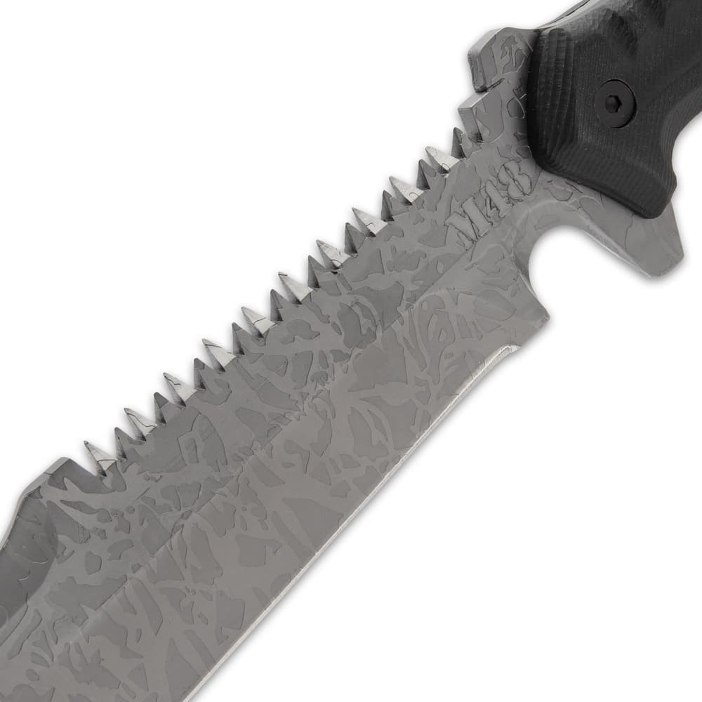 Upclose view of a M48 titanium electroplated blade with a partial sawback spine with jagged edges and a "M48" logo on the blade. image number 3
