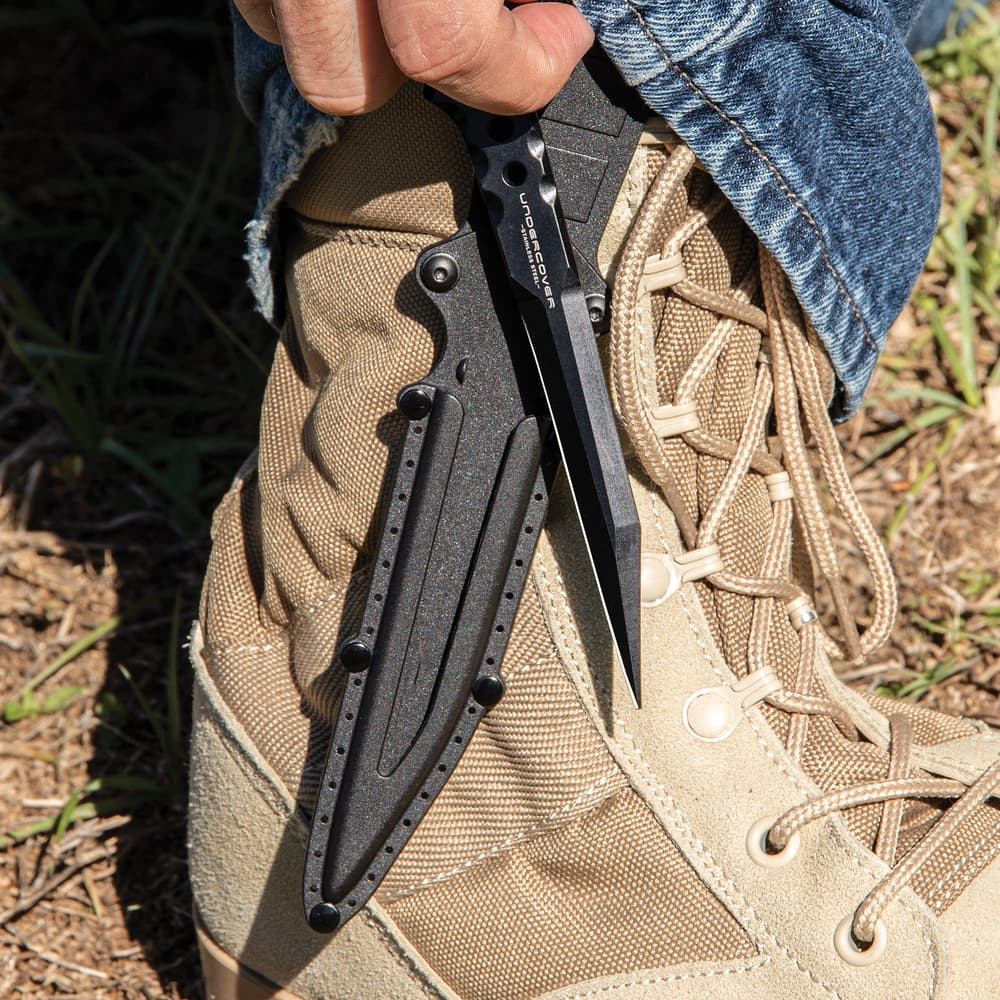 "Undercover" stinger knife being held in front of a black knife sheath attached to a military-style boot. image number 3