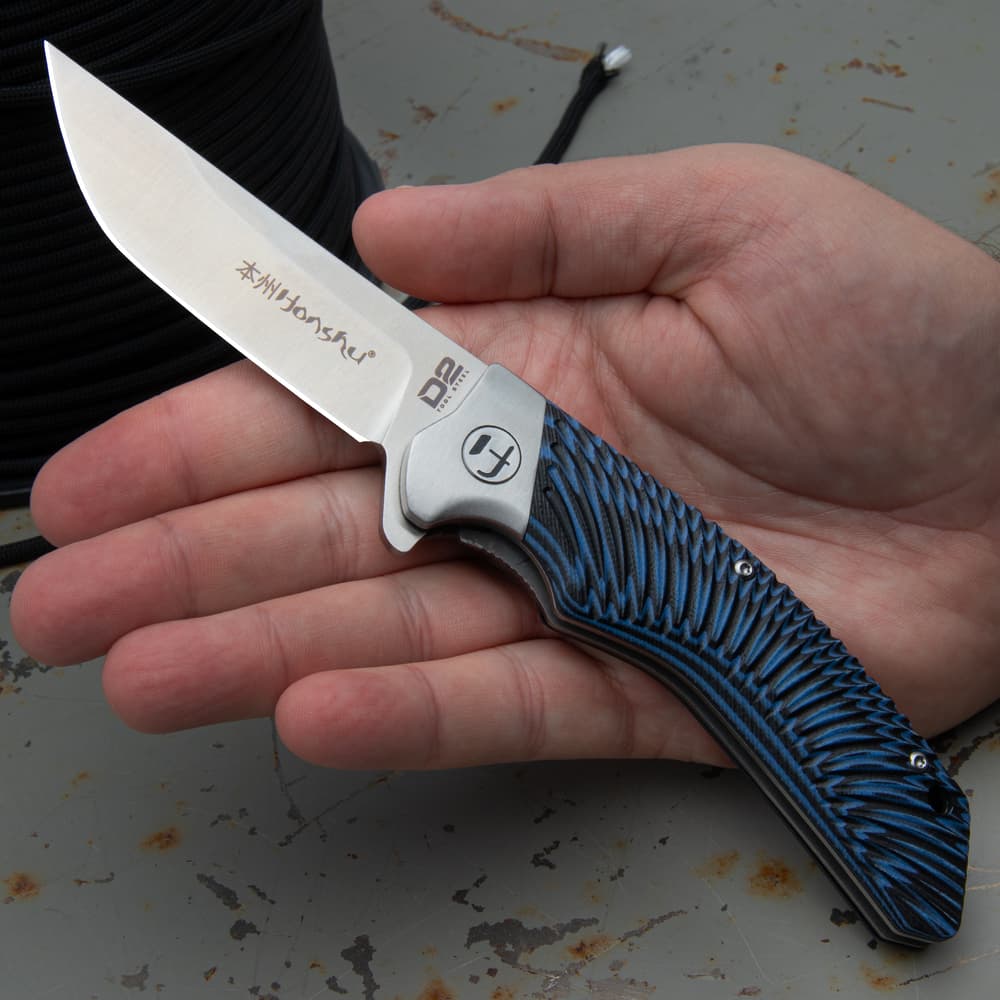 Open pocket knife with an inscription of "Honsu" on the blade and a tie-dye style blue and black handle. image number 3