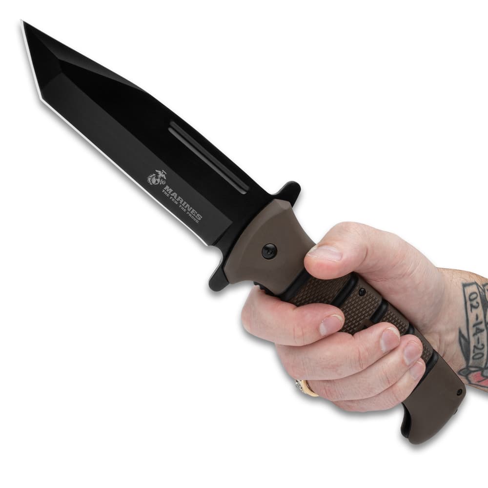 An angled view of the USMC Tanto Maximum Pocket Knife with black, non-reflective blade and stacked TPR handle. image number 3