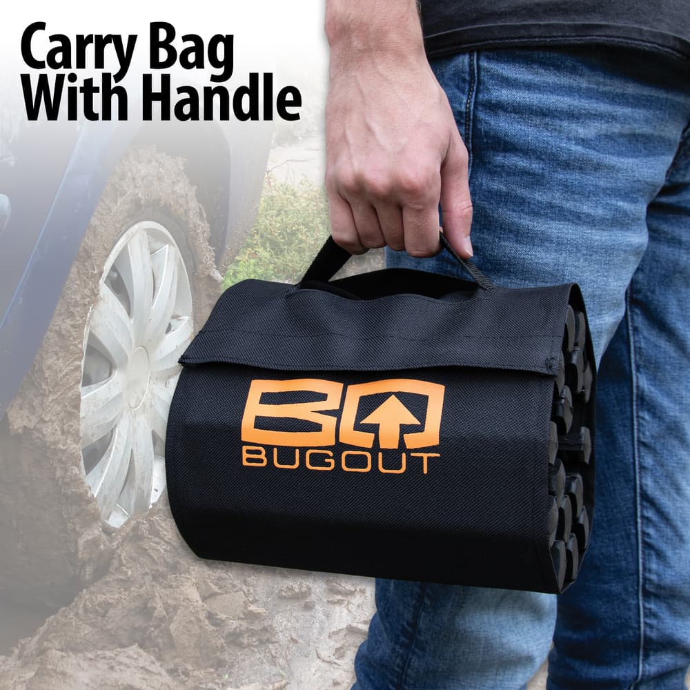 The BugOut Roll-Up Traction Tracks are shown rolled into its carry bag held with the bag logo facing outward. image number 3