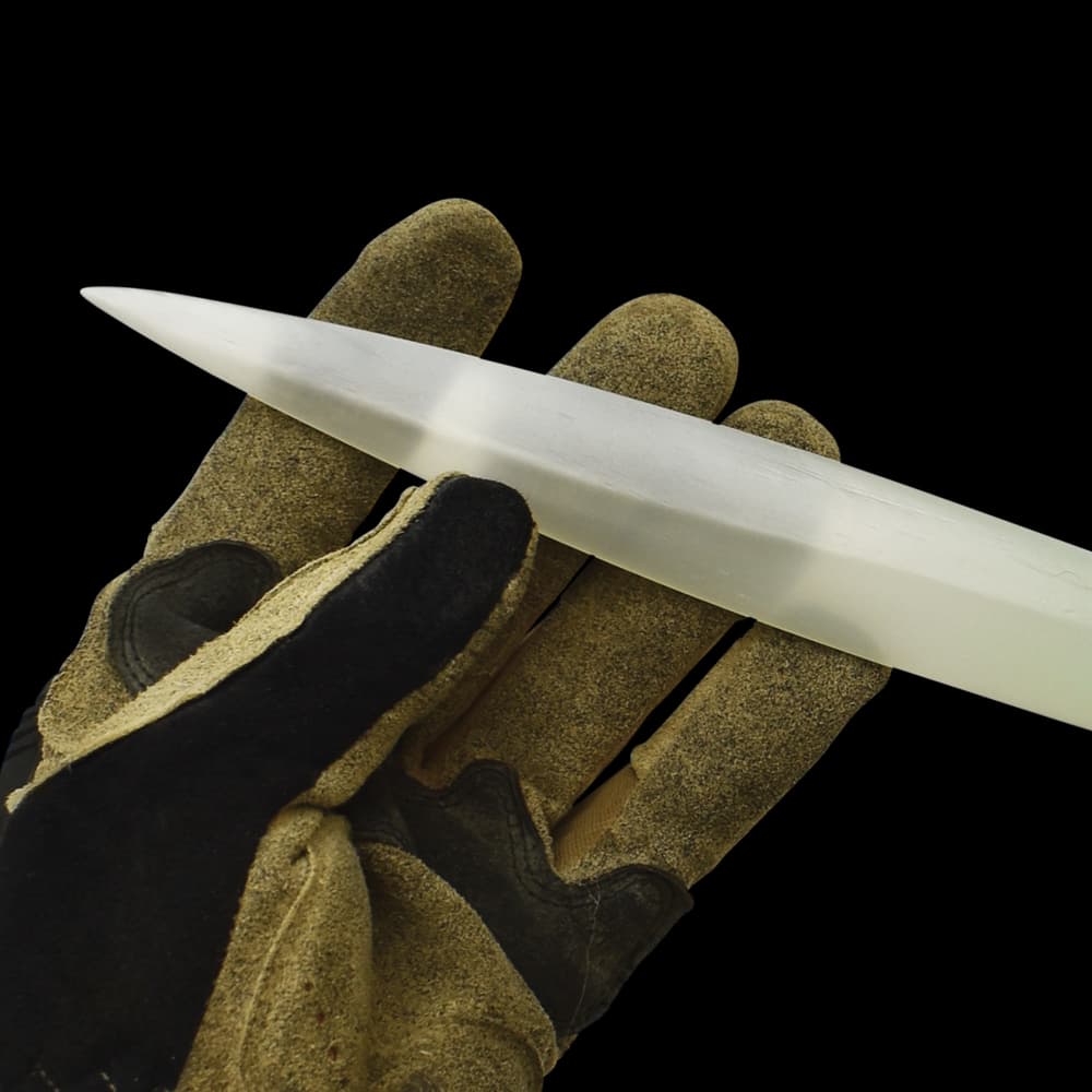 Shining silver double edged narrow blade being held at its' end by a glove covered hand. image number 3