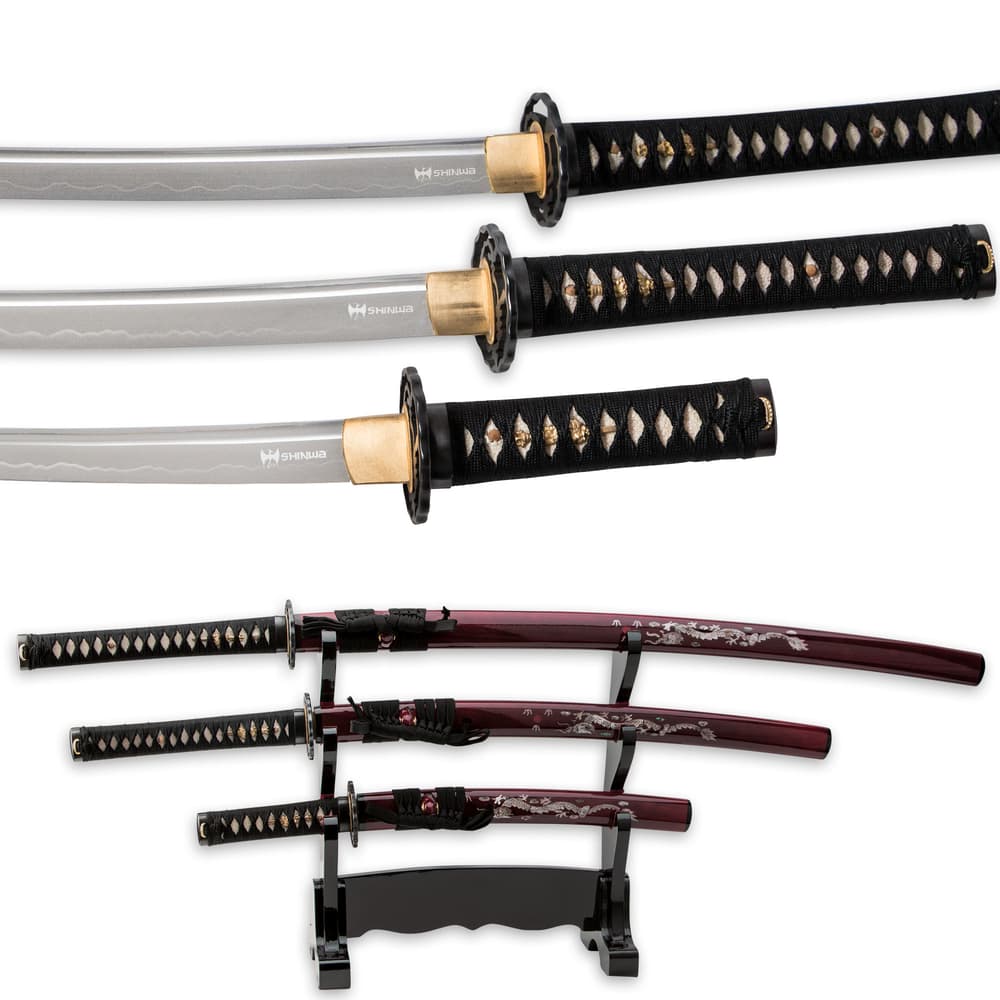 All three swords have a white ray skin handle with black cord wrapped around it and brass menuki and have a wooden display. image number 3