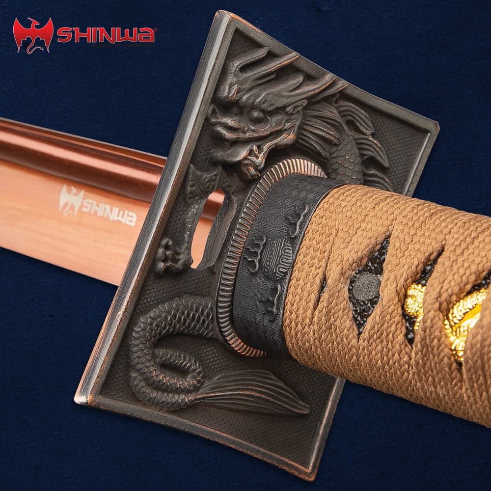 The sea dragon embossed tsuba is shown in detail just above the “Shinwa” engraving on the copper colored blade. image number 3
