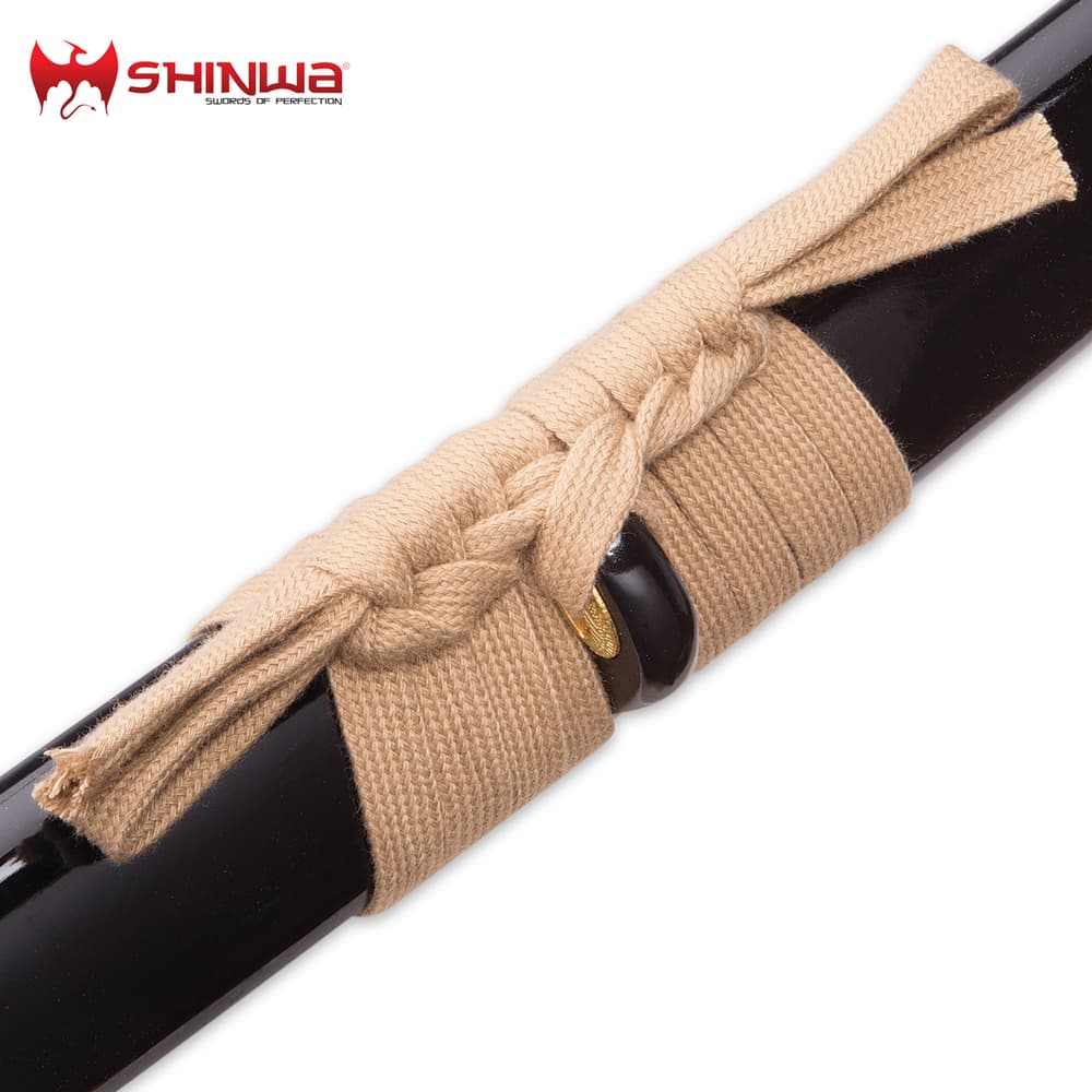 Detailed view of the tan hanging cord wrapped around the black scabbard. image number 4