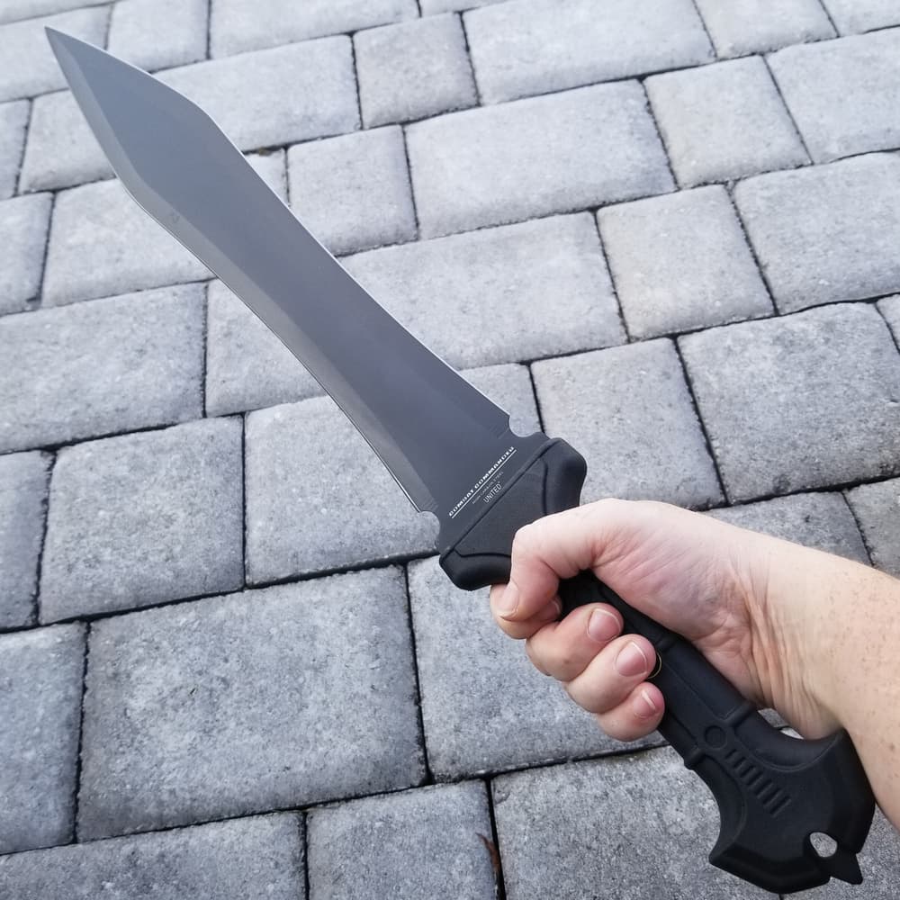 A hand holding the tpr rubberized handle of United Cutlery Combat Commander gladiator 1060 stainless steel sword with a sharp point image number 4