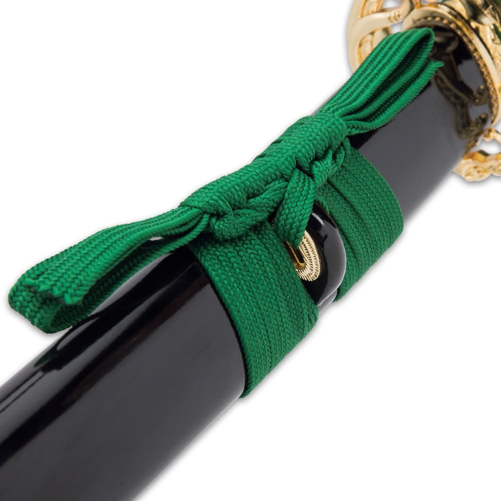 Close view of black lacquered scabbard accented with green nylon cord wrapped around the brass knob image number 6