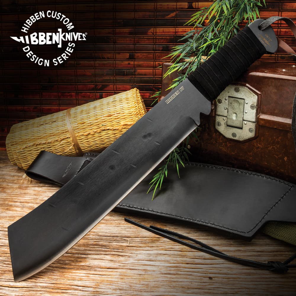 Gil HIbben IV Machete Knife is one solid piece of 1090 carbon steel and has a black cord wrapped handle, shown on wooden background. image number 0