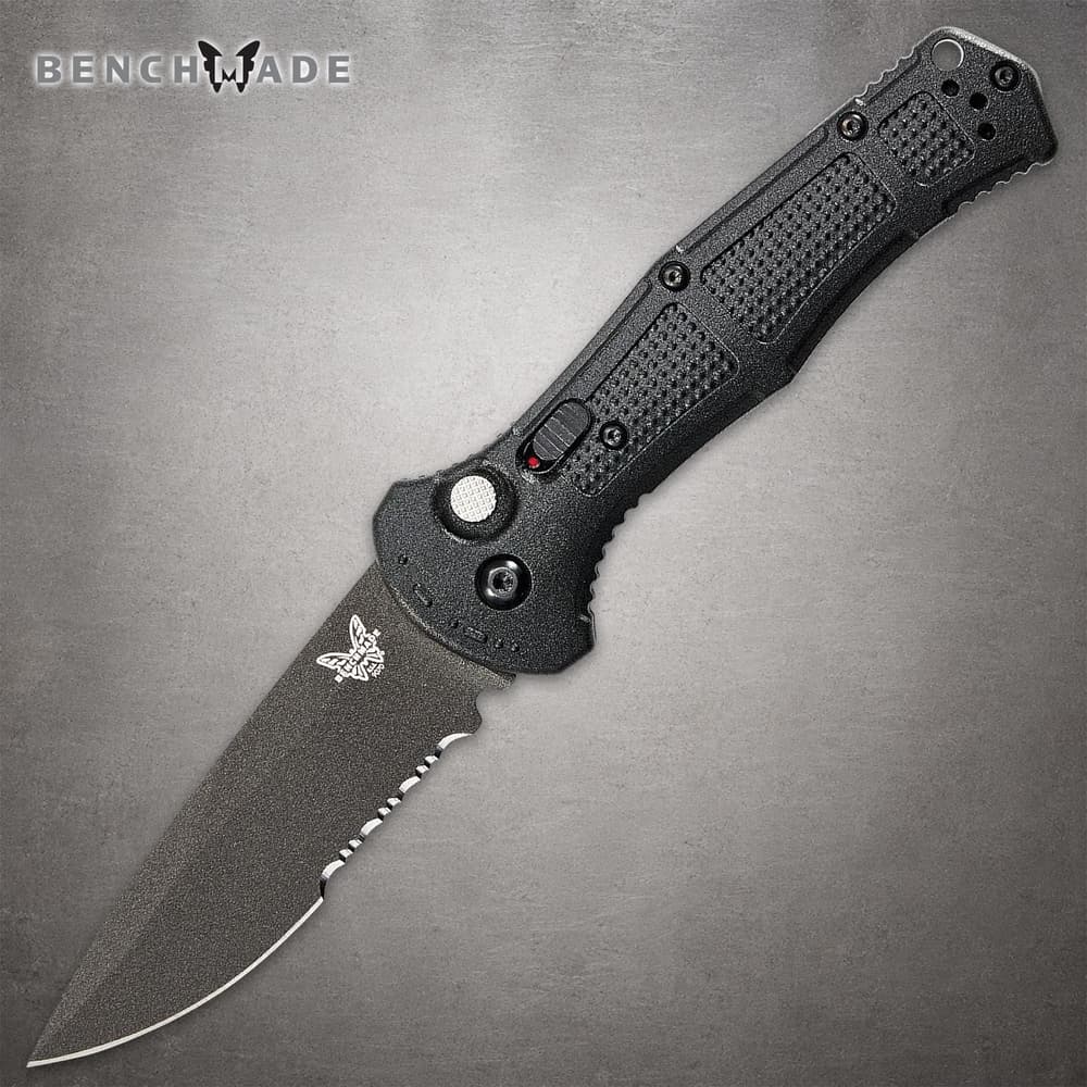 Black folding knife with textured handle and serrated blade image number 0