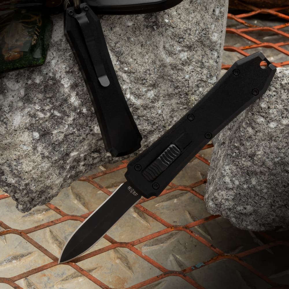 Mini non-reflective black OTF pocket knife with double edged stainless steel blade. image number 0