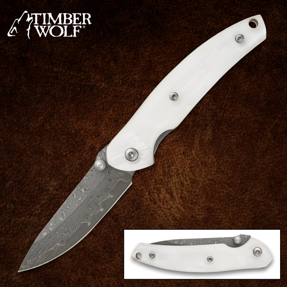 White-handled folding knife with Damascus blade on brown background image number 0