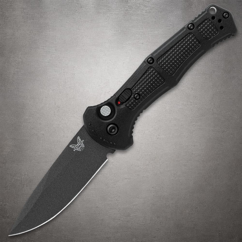 Black folding knife with textured handle on gray background image number 0