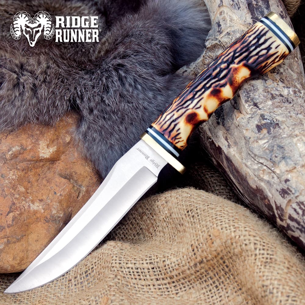 Knife with a burnt jigged bone handle on fur and burlap image number 0