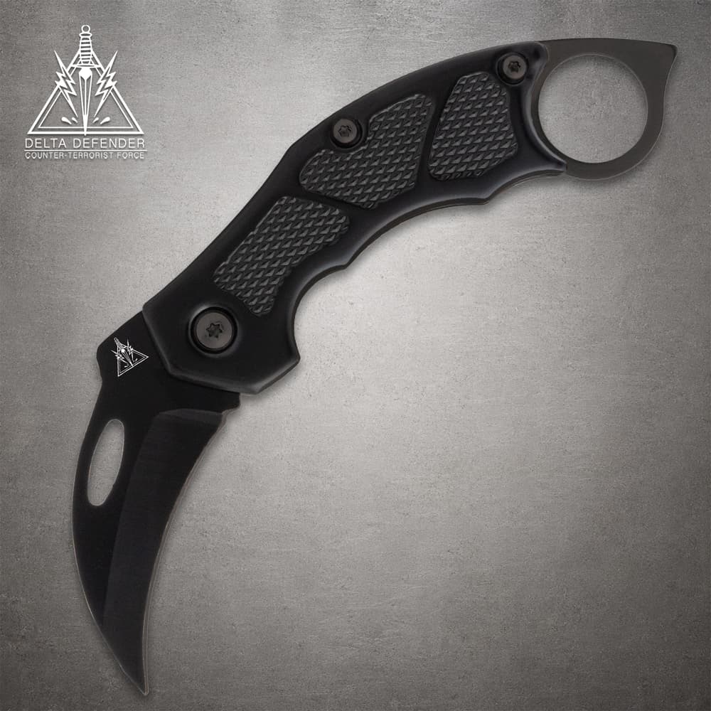 Black folding knife with textured grip and ring handle image number 0