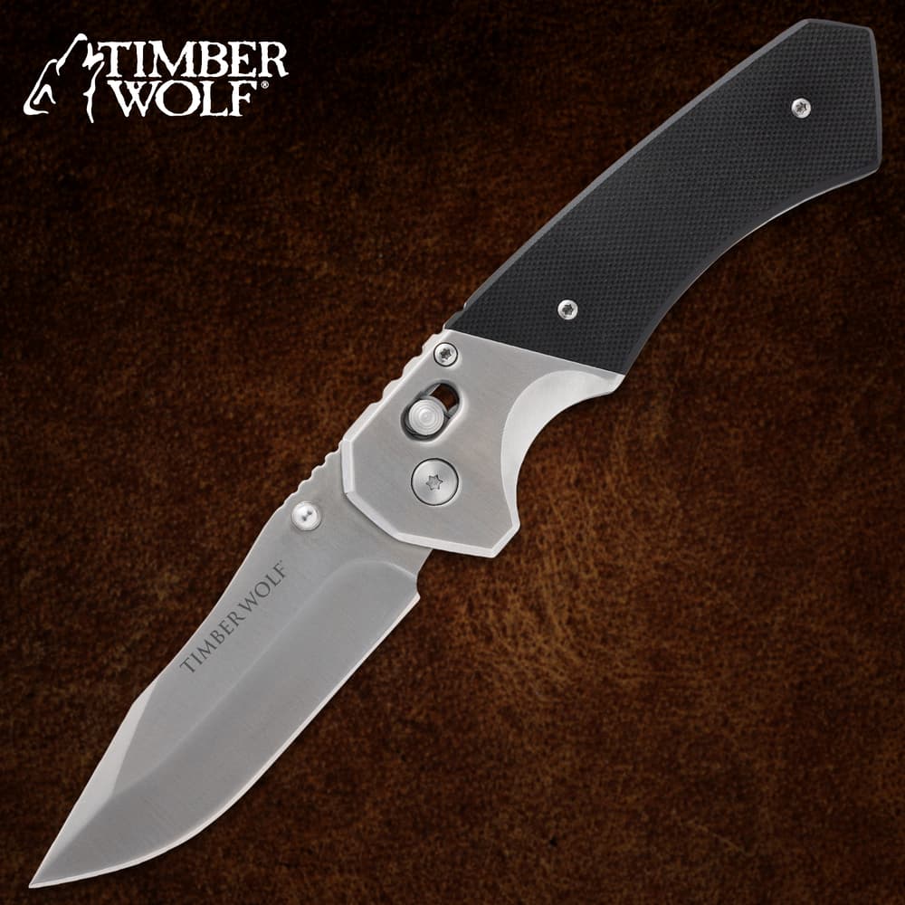 Folding knife with black handle on brown background image number 0