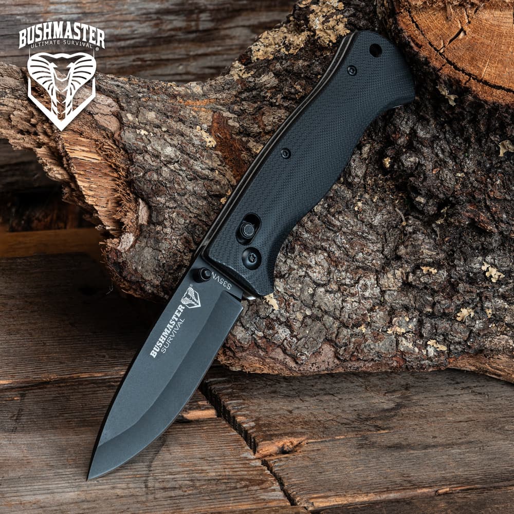 Black folding knife on tree bark with Bushmaster logo image number 0