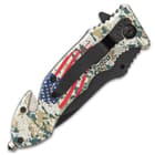 The assisted opening pocket knife has a 3 3/4” black stainless steel blade and a camouflage aluminum handle with an American flag