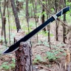 The machete with black sawback spine is shown cutting into a tree.