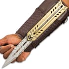 The arm sheath is constructed of faux leather and nylon canvas and fastens onto the forearm with Velcro and buckle straps