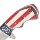 Upclose angled view of a fixed blade bowie with a decorative American flag handle featuring a “2nd Amendment” print. 