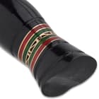 The handle is crafted of black bull horn with a brass pommel, accented with bands of red and green wood, separated by brass spacers