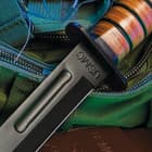 7" black finished steel blade fighter knife with a stacked leather handle on a background of green utility gear.
