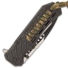 The tough, black ABS handle features camouflage paracord woven into it, extending into a short lanyard, and it has a glass breaker