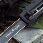 Detailed view of the stainless steel blade ejected from the front of the knife using a trigger and spring mechanism.