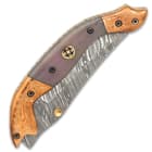 The gently curved handle scales are dyed bone, accented with a brass rosette and brass and steel fileworked liners