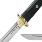 Zoomed view of the 1060 high-carbon steel blade point and brass guard and blade collar above the “Honshu” logo on the blade. 