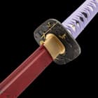 The wooden handle is wrapped in faux rayskin with purple cord and the brass tsuba has two Samurais fighting on horseback