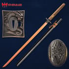 Copper japanese sword with black scabbard to secure sharp blade lay adjacent to square tsuba with an embossed detailed dragon
