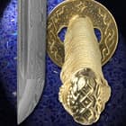 Detailed view of both the Damascus steel blade of the sword and the brass guard and pommel of the handle. 