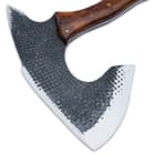 The 8” wide axe head has been crafted of 1095 carbon steel with a hand-hammered pattern, giving it a rough-forged texture